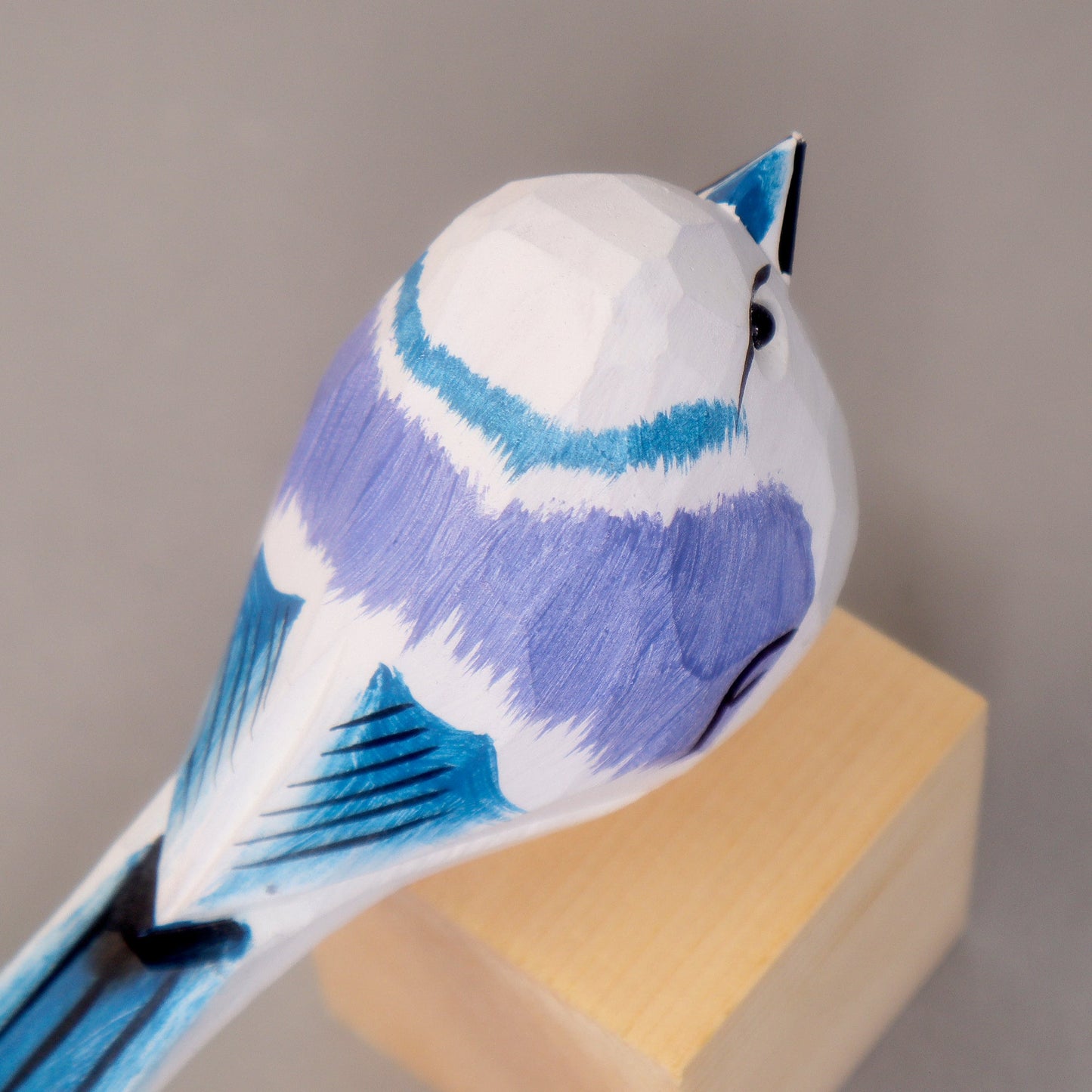 Blue and white bird figurine on a wooden stand against a gray background