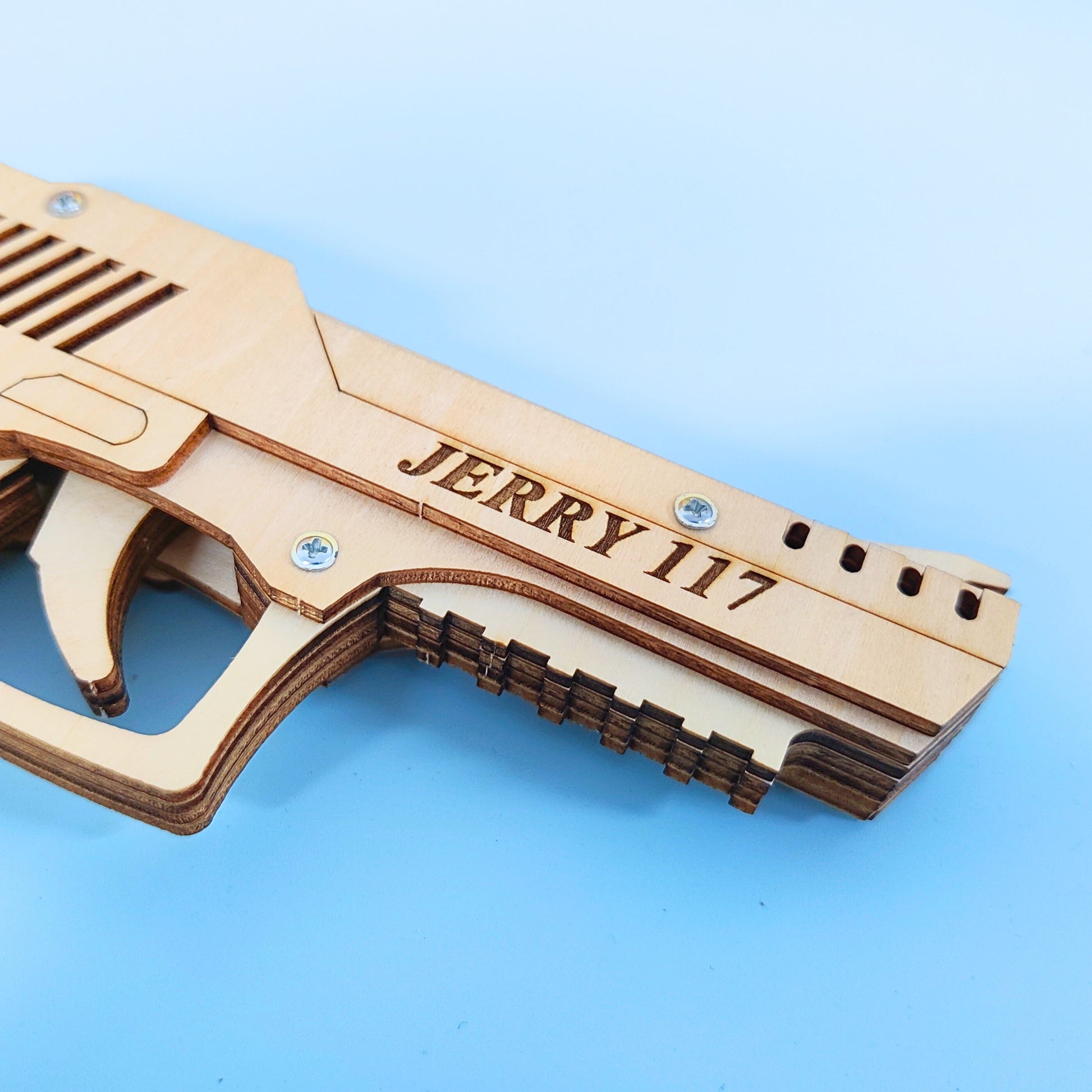 Wooden gun model with 'JERRY 117' engraving on a blue background