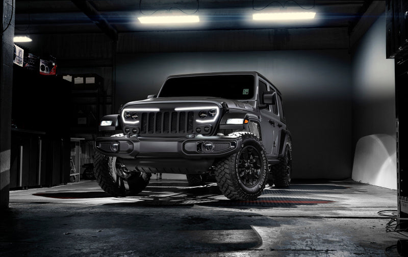 Black Jeep Wrangler in a dark garage with bright lights.