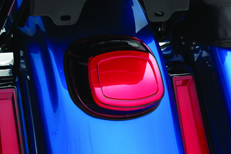 Close-up of a blue motorcycle with a red light on a dark background