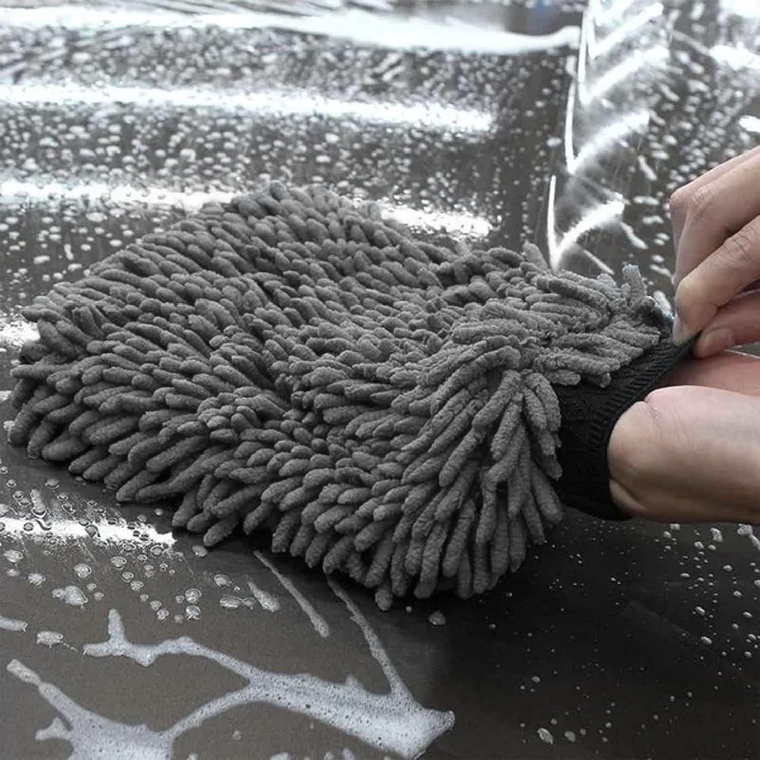 Microfiber cleaning mitt being used on a car window with soapy water.