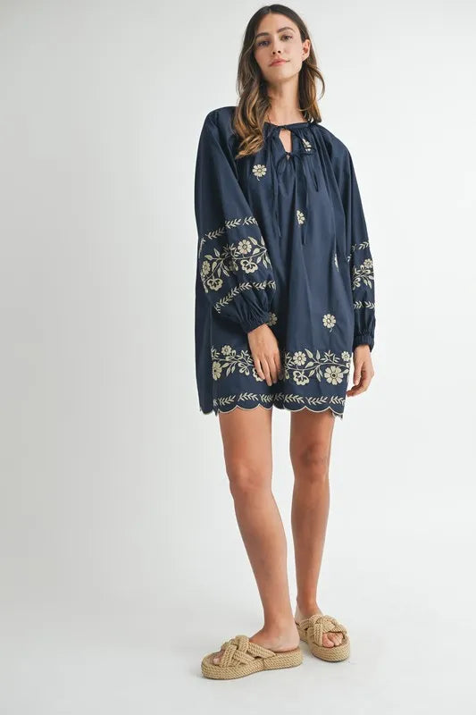 Woman wearing a navy blue dress with floral embroidery on a white background