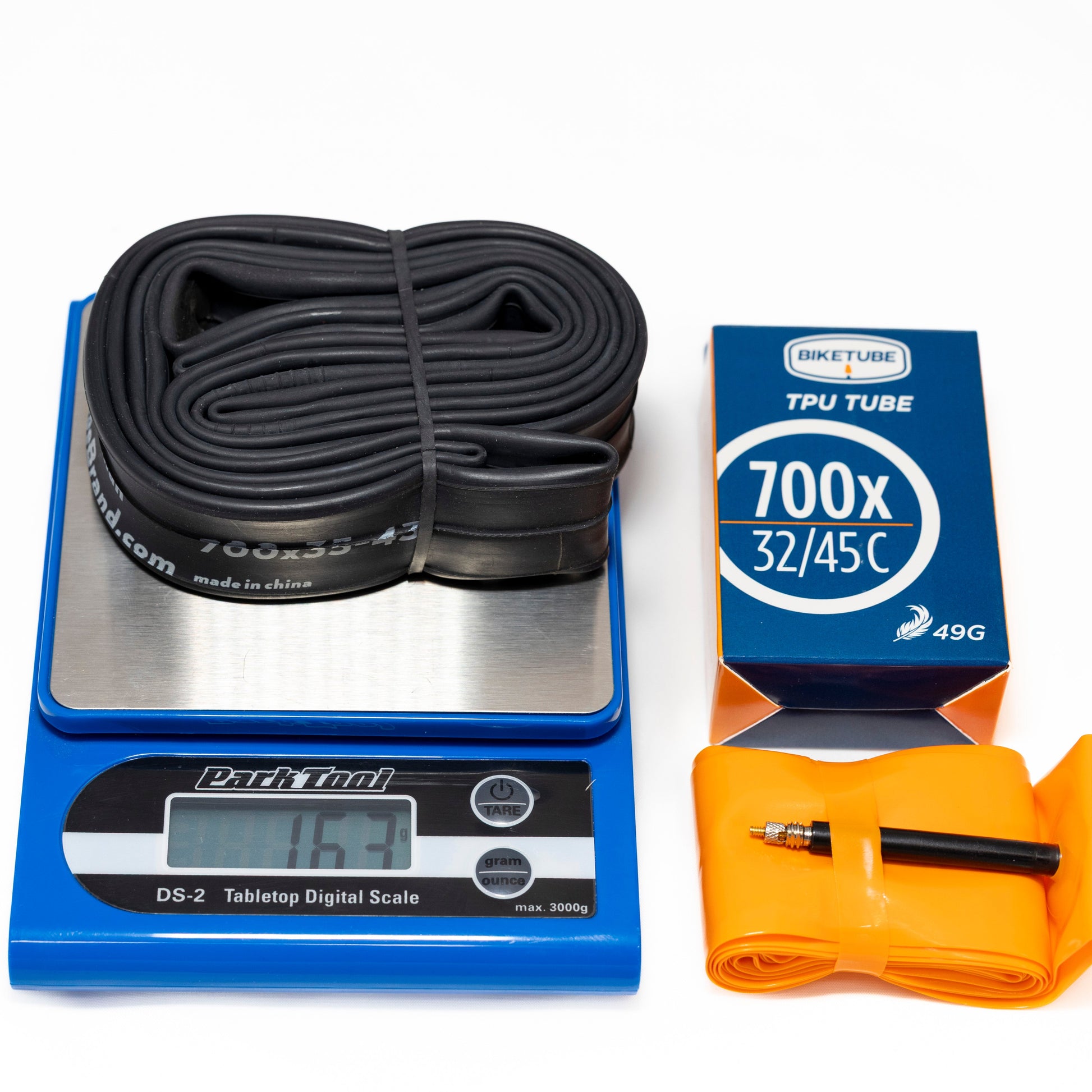 Bicycle inner tubes on a digital scale with packaging and a pump on a white background