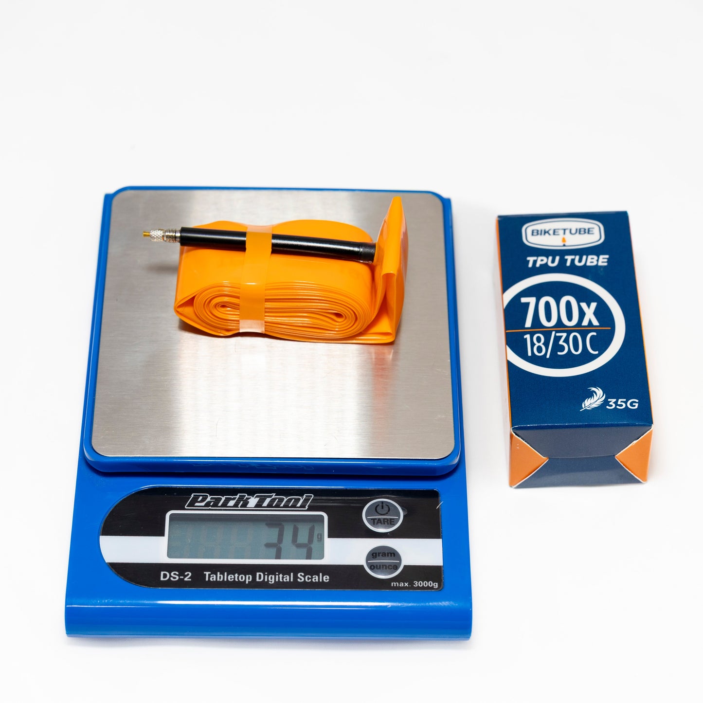 Orange bicycle tube on a digital scale with a box labeled '700x18/30c' in the background.