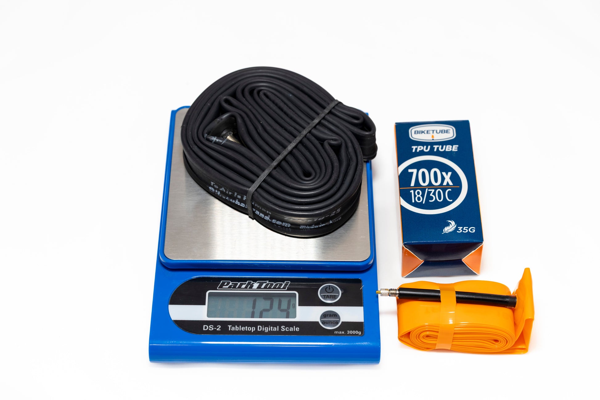 Cycling tube on a digital scale with packaging and an orange tool on a white background