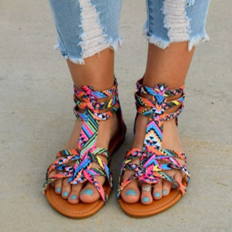 Colorful braided sandals worn with ripped jeans on a neutral background