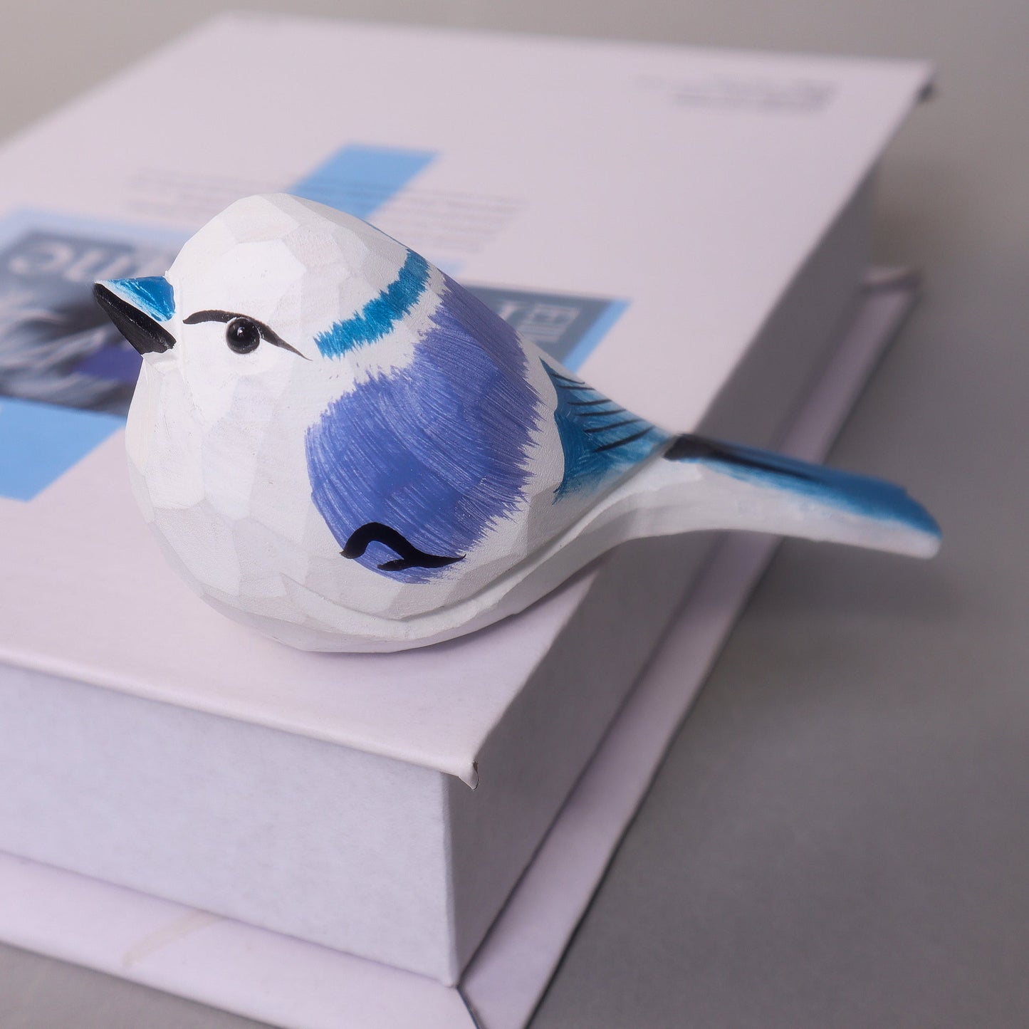 Decorative bird figurine with blue and white colors on a stack of books.