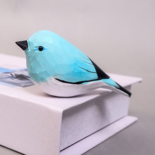 Blue bird-shaped object on a white surface with a gray background