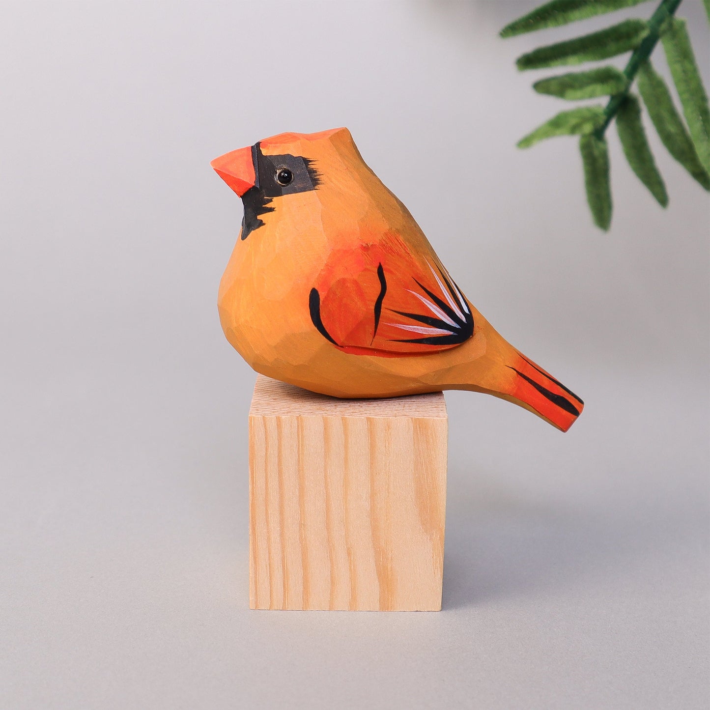 Wooden cardinal figurine on a wooden block with a light gray background