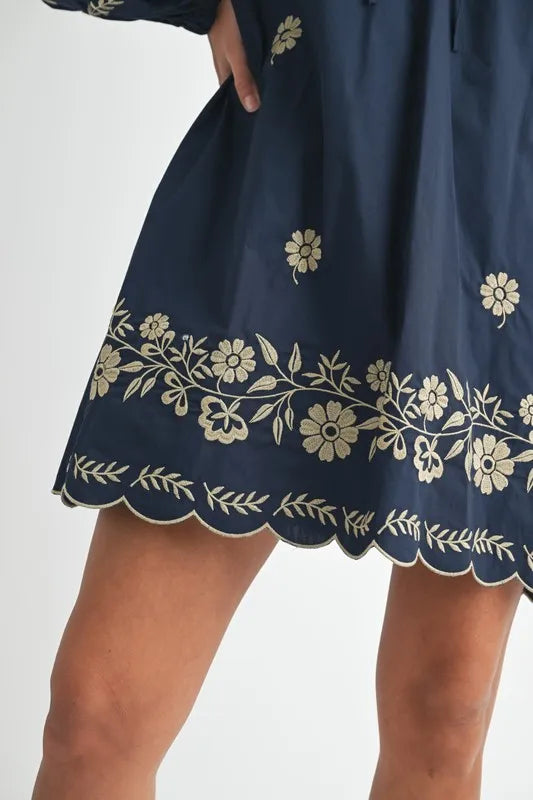 Navy blue dress with white floral embroidery on a plain background