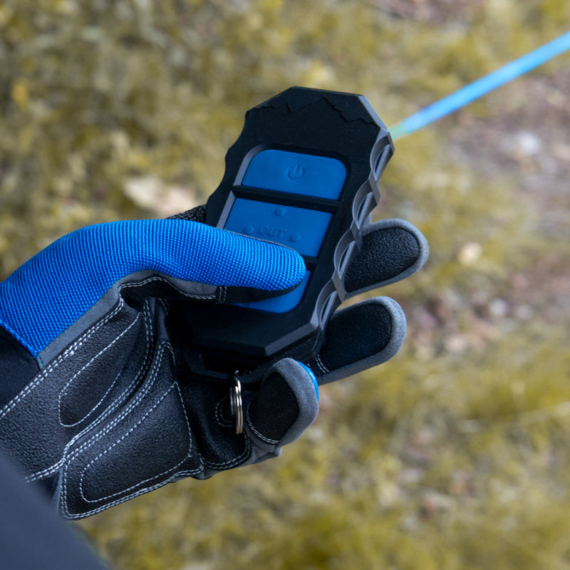 Close-up of a gloved hand holding a device with buttons against a blurred natural background