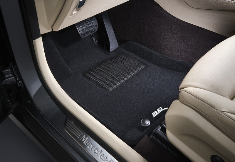 Car interior with black floor mats and Mercedes-Benz logo.