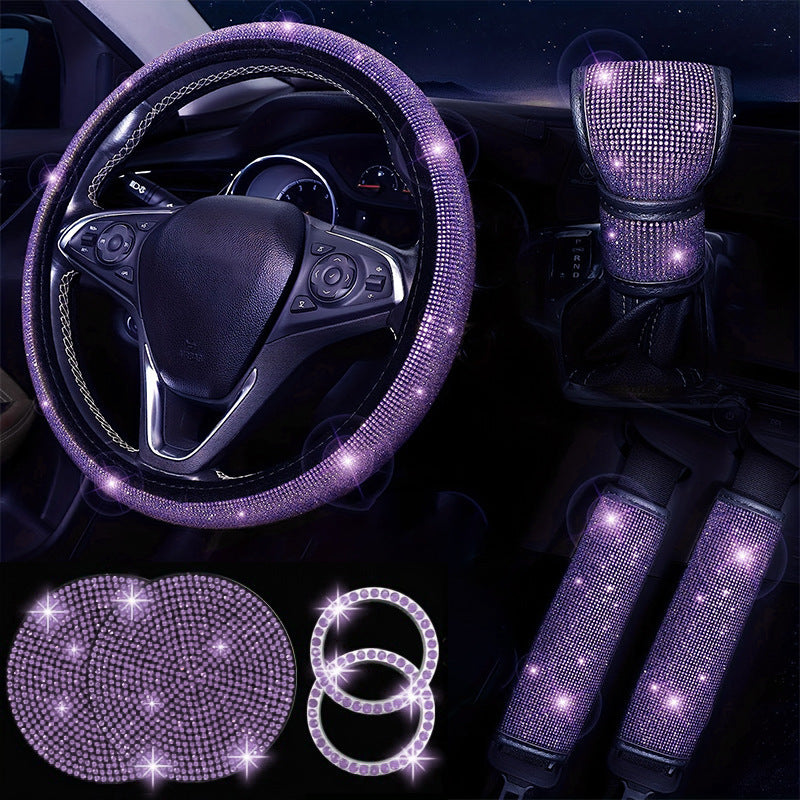 Car interior set with purple bling steering wheel cover, gear shift cover, cup holder, and coasters on a dark background.