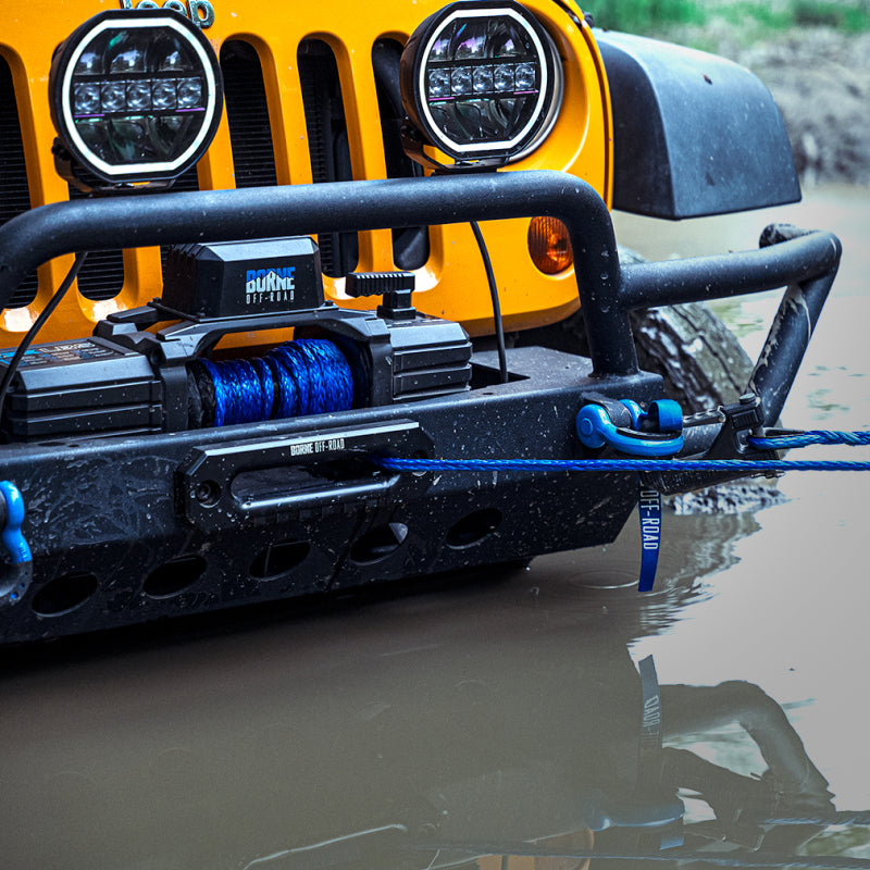 Yellow off-road vehicle with a winch and blue rope on a muddy surface