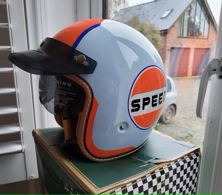 Vintage-style helmet with 'Speed' logo on a box, outdoors.