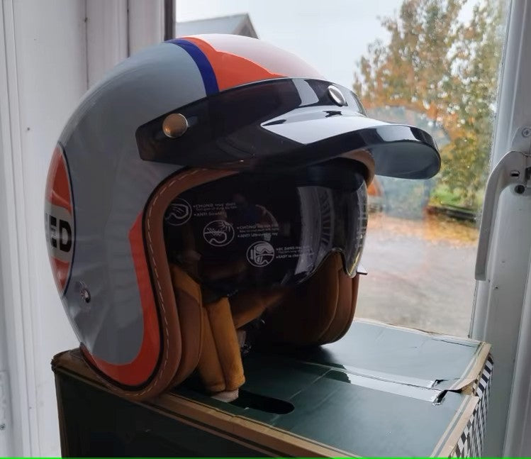 Helmet with orange and blue design on a stand indoors