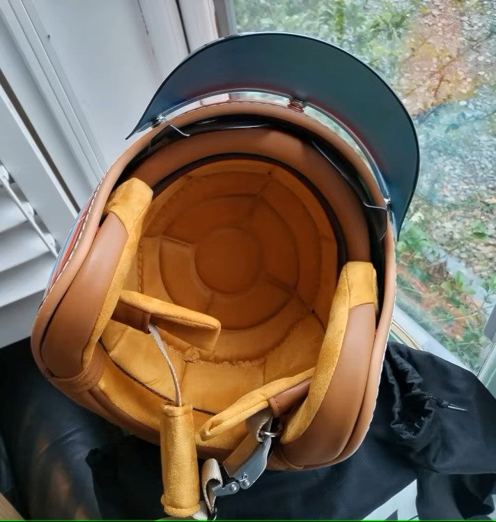 Close-up of a vintage-style motorcycle helmet with brown interior and black exterior.
