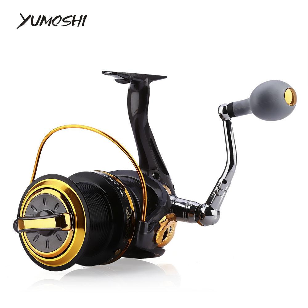 Fishing reel with gold and black design on a white background, featuring the YUMOSHI brand.