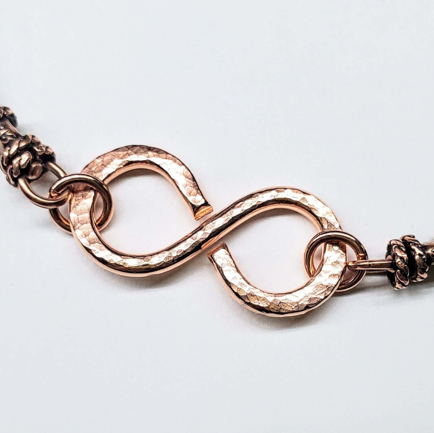 Rose gold bracelet with an infinity symbol on a light gray background