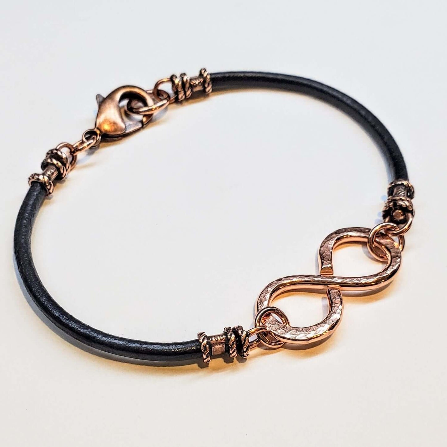 Bracelet with rose gold infinity symbol on a light gray background