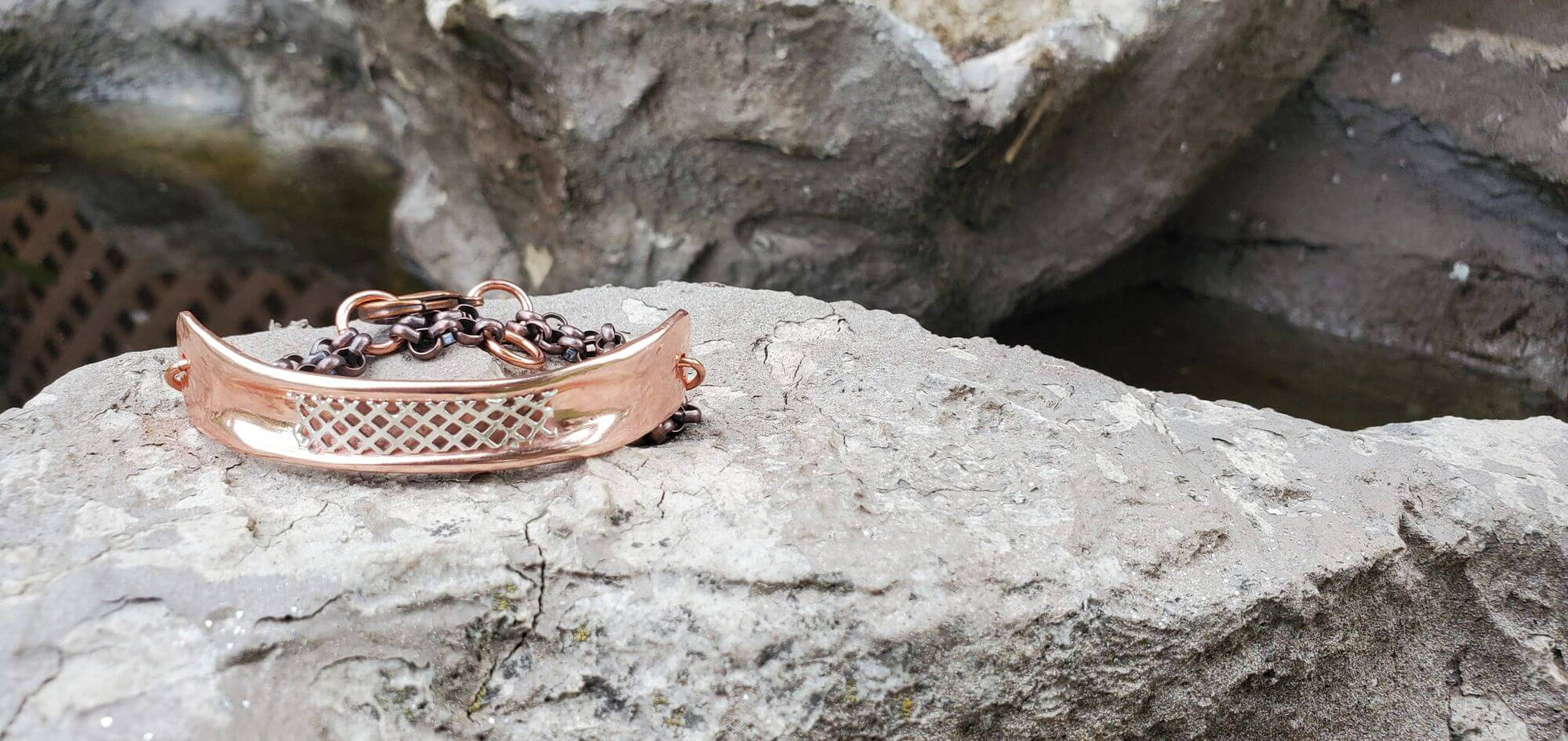 Rose gold bracelet with dark beads on a rock