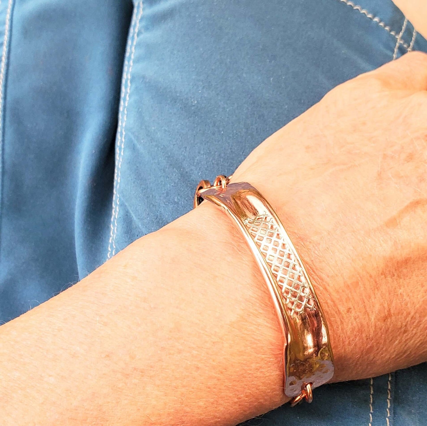 Rose gold bracelet on a wrist with a blue denim background