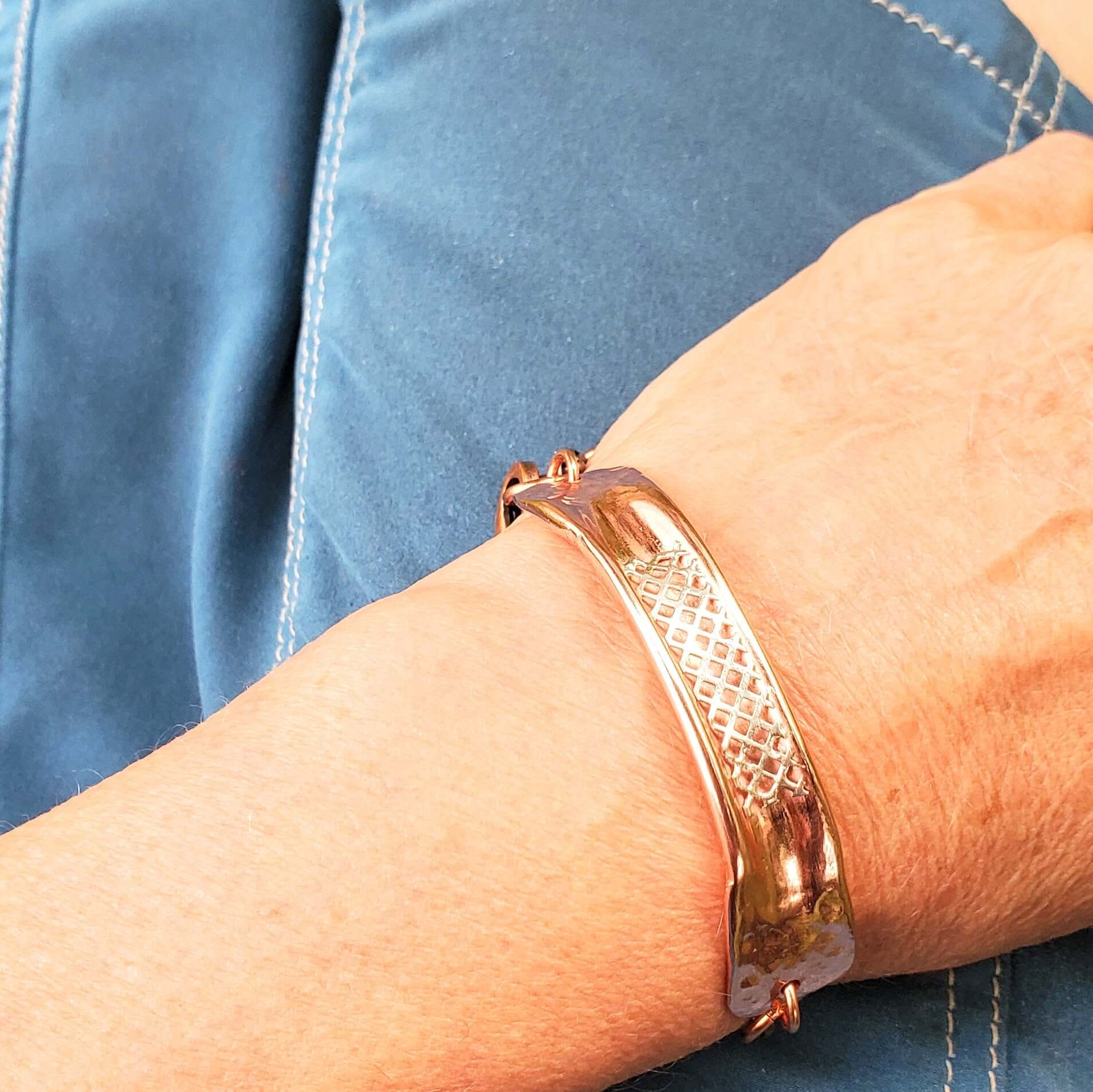 Rose gold bracelet on a wrist with a blue denim background