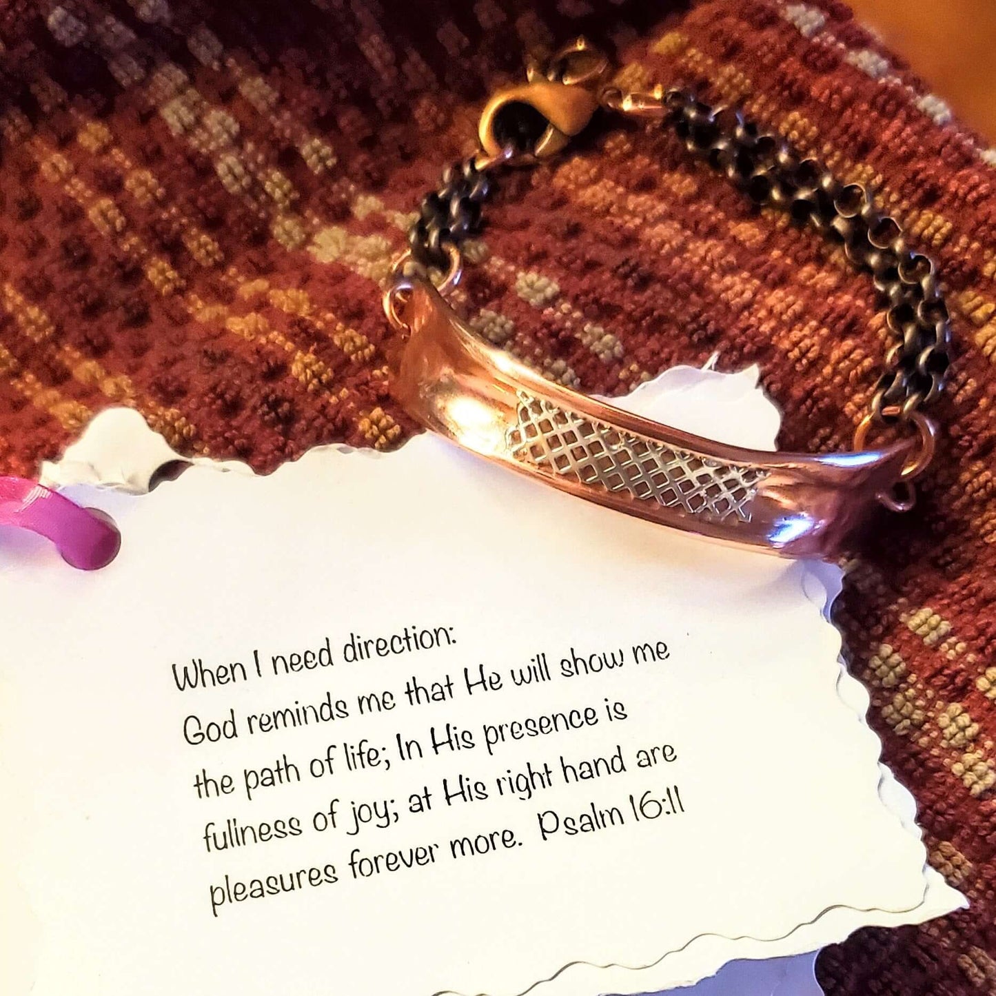 Bracelet on a paper quoting Psalm 16:11 on a textured fabric background