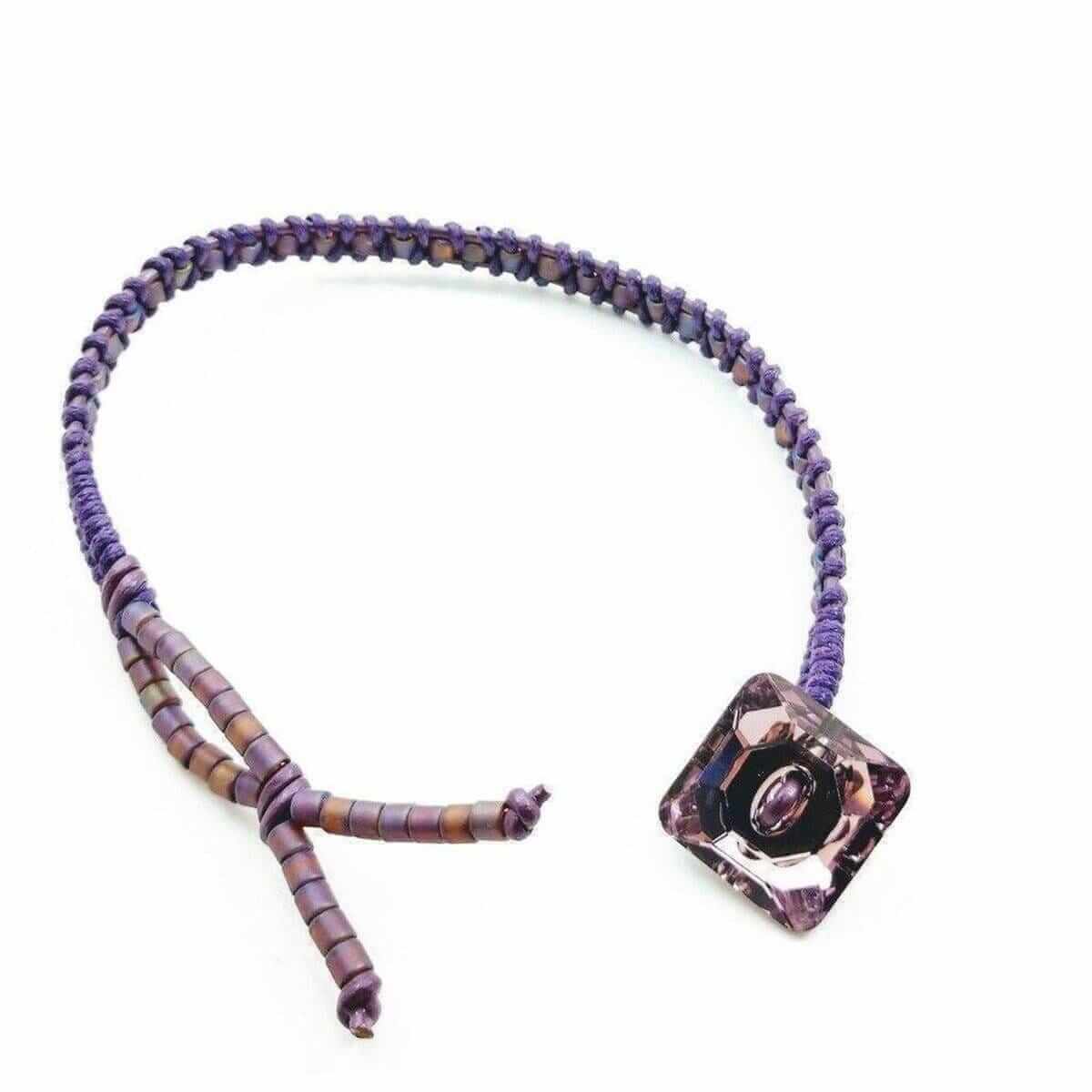 Bracelet with a purple and brown beaded design and a square pendant on a white background