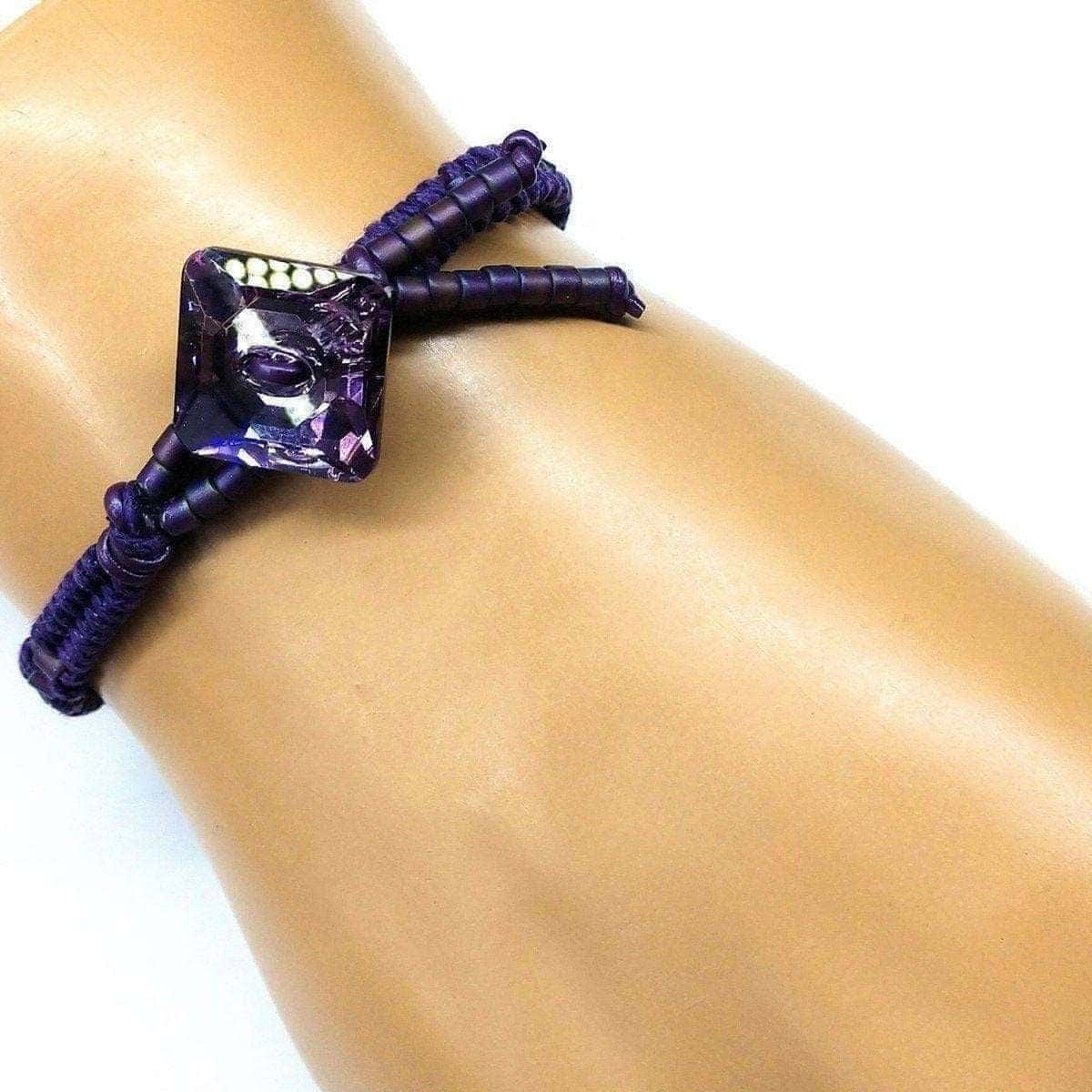 Purple beaded bracelet on a wrist against a white background