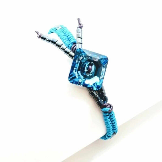 Blue and black braided cord with a clear cube-like object on a white background