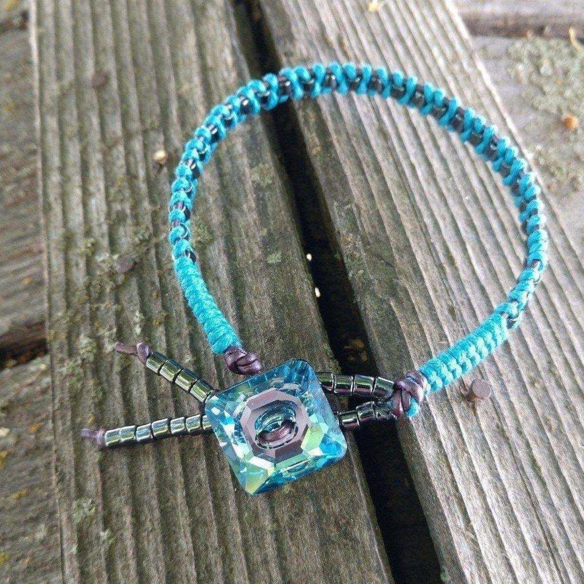 Turquoise beaded bracelet with a square glass charm on a wooden surface