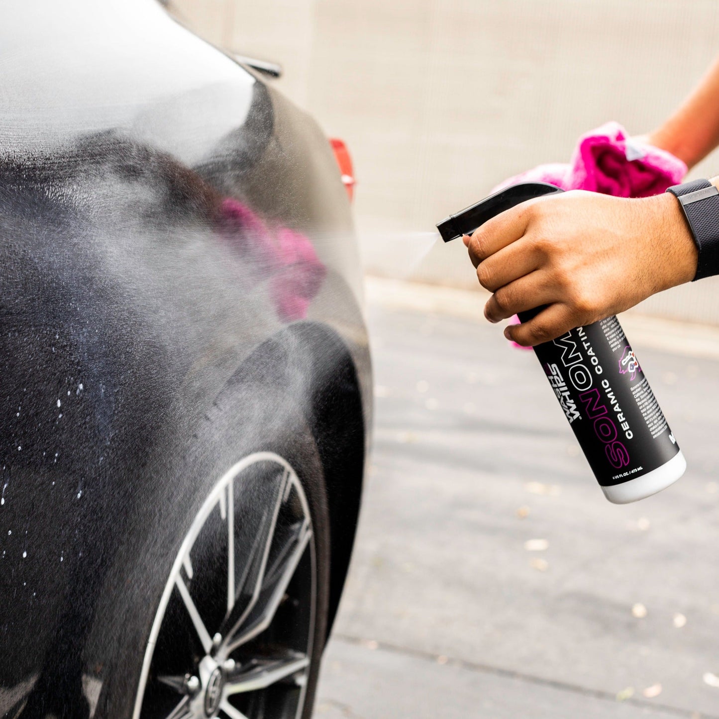 Person cleaning a car with a spray bottle .