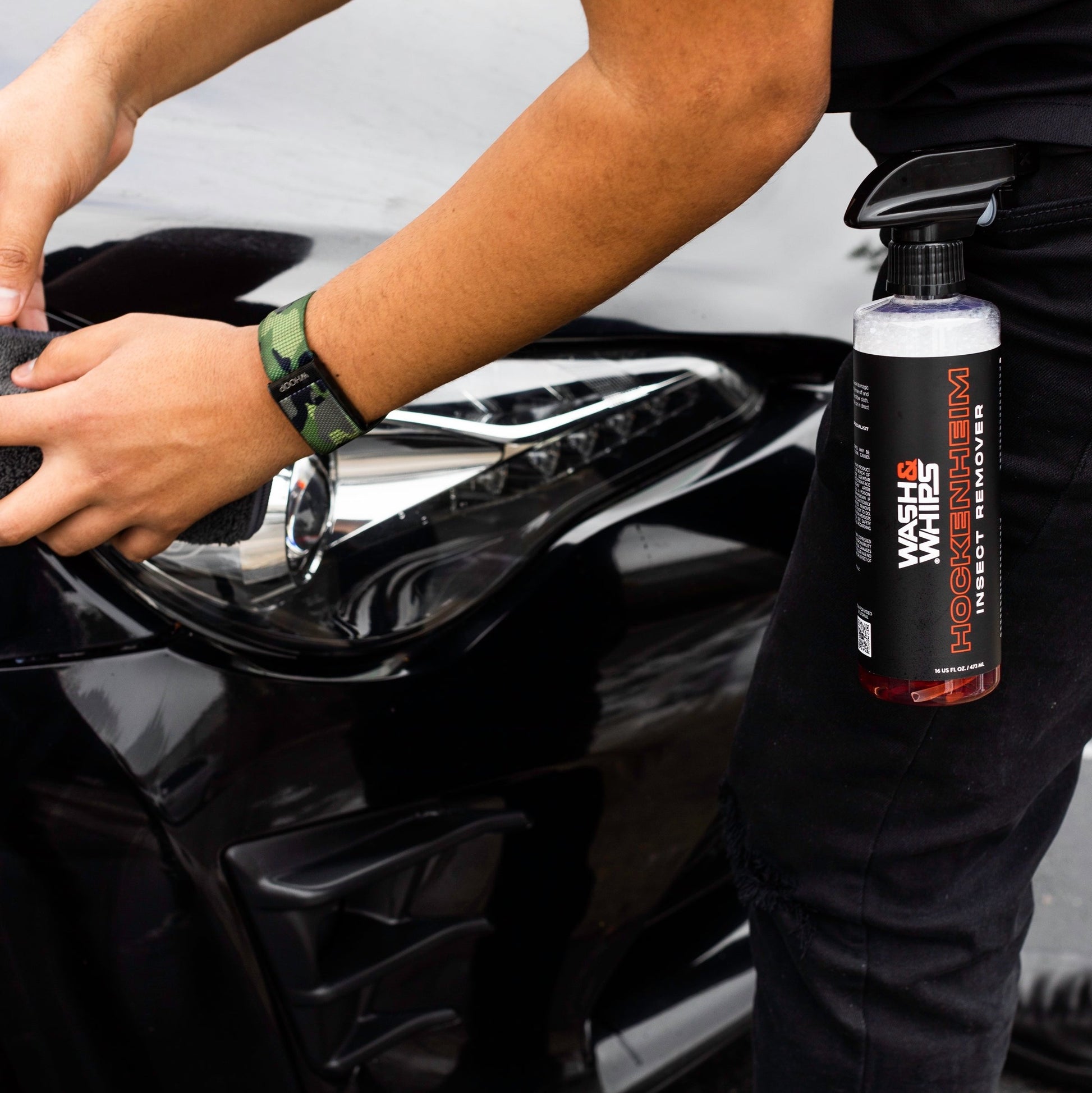 Person cleaning a car with a bottle of wash and wax product.