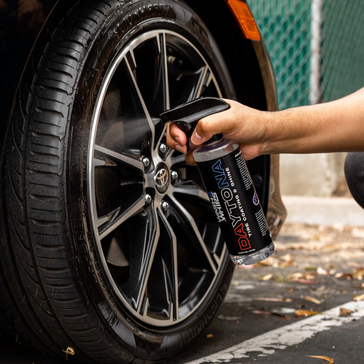 Person using a can of Daytona Cleaner on a car tire rim.