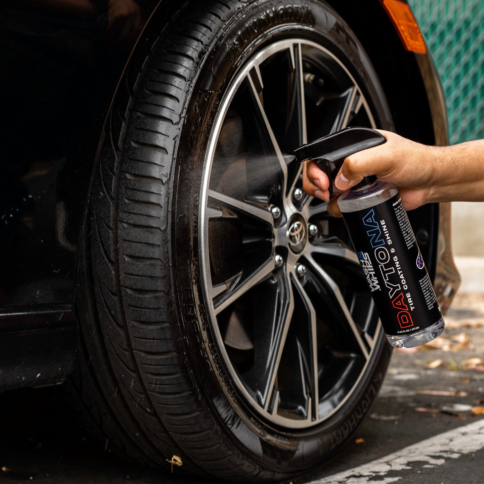Person using a can of Daytona Wheel Cleaner on a car wheel.