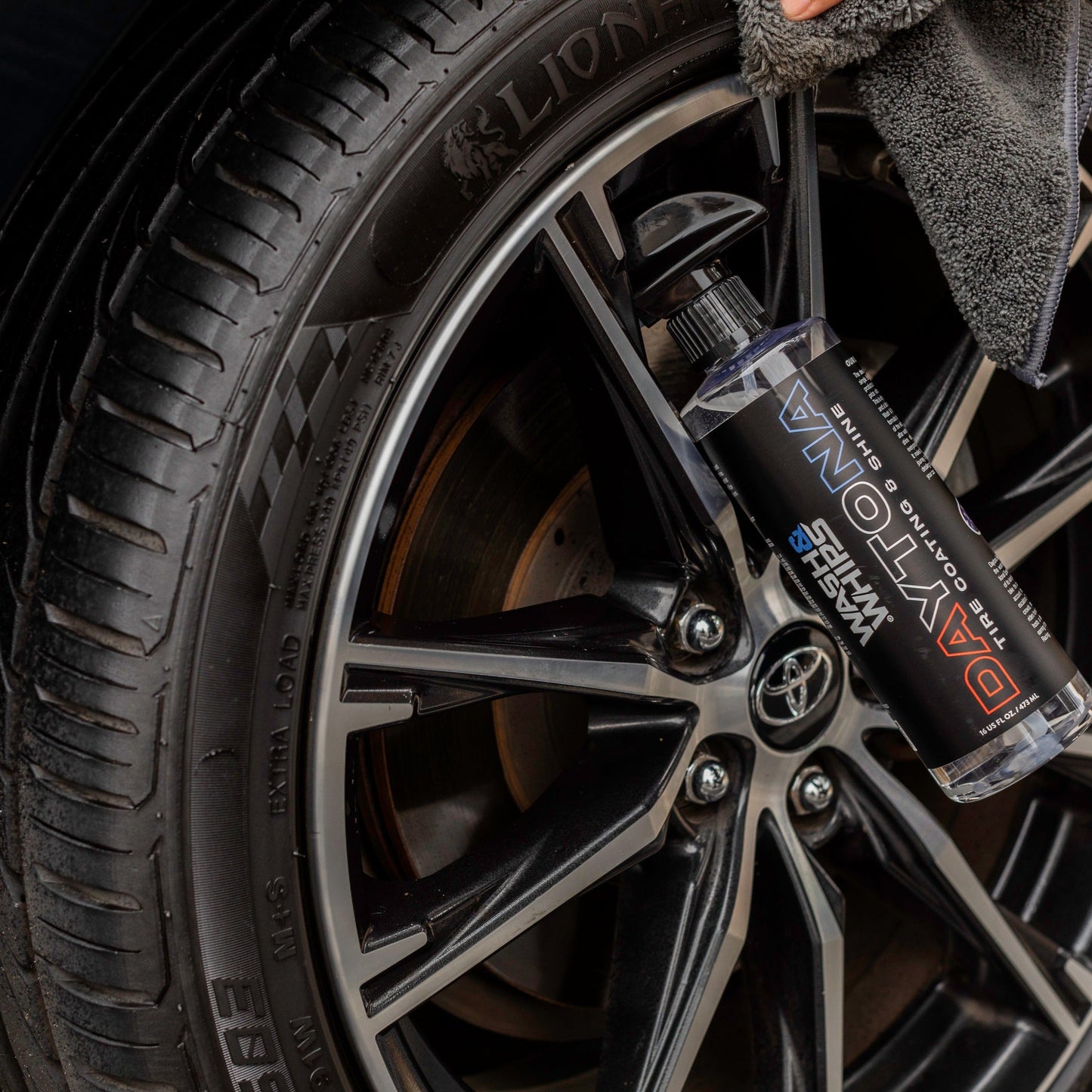 Close-up of a car wheel with a can of Loctite product on a black background