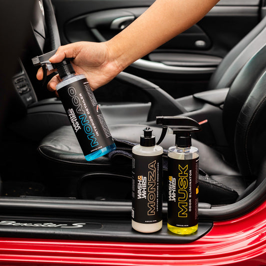 Person holding a car care product with bottles of car care products on a car dashboard.