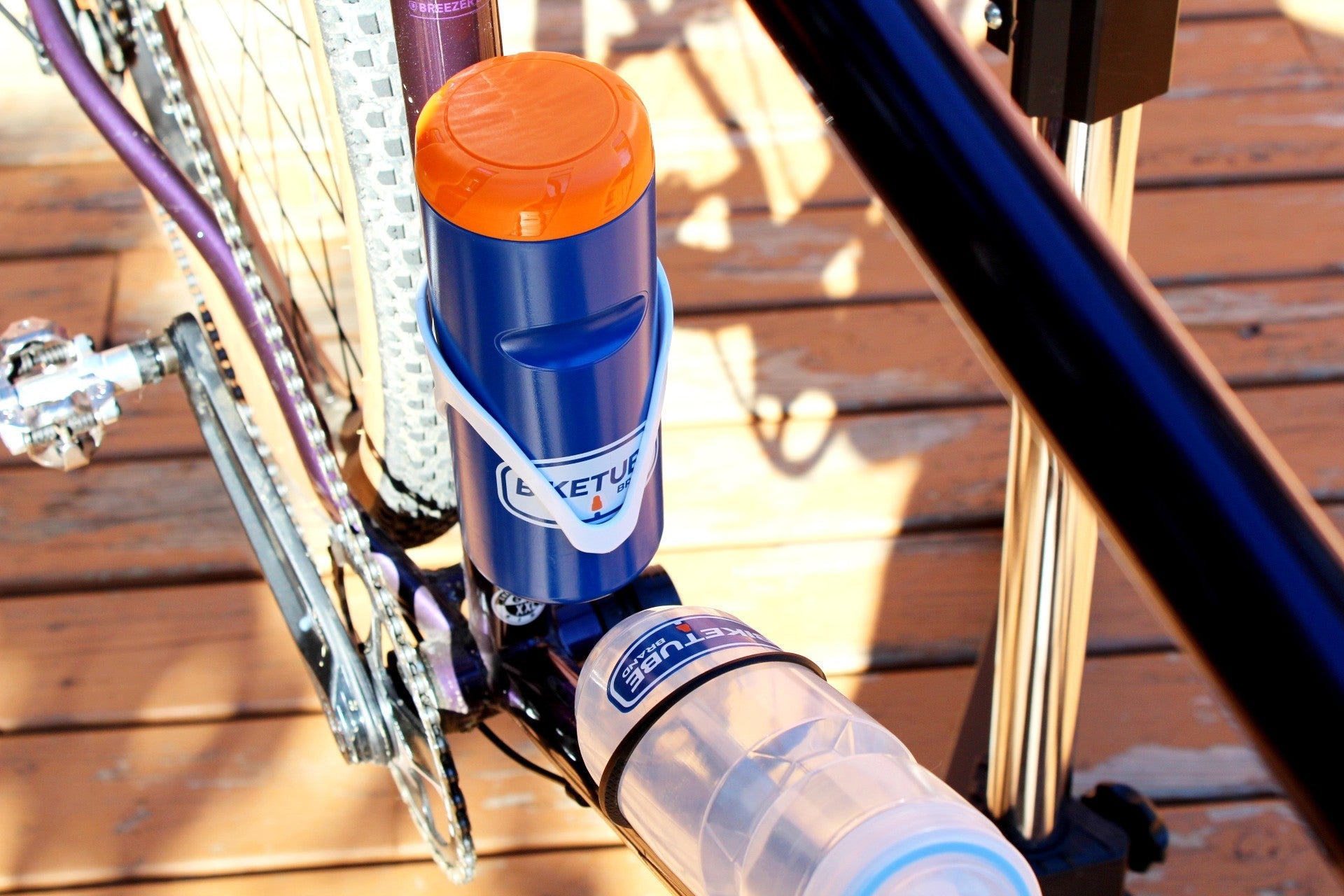 Bicycle water bottle holder with a bottle attached on a wooden surface