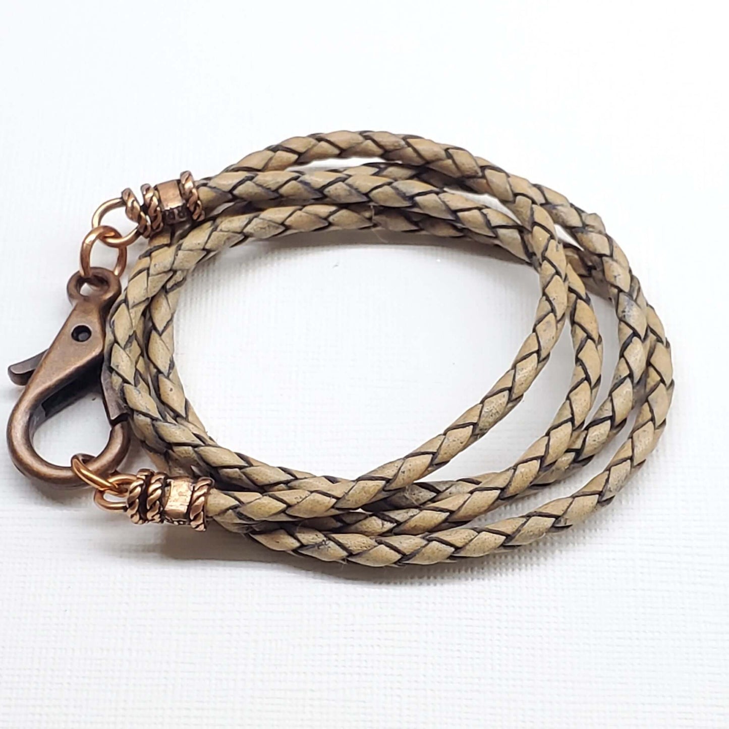 Beige braided leather necklace with bronze clasp on a white background