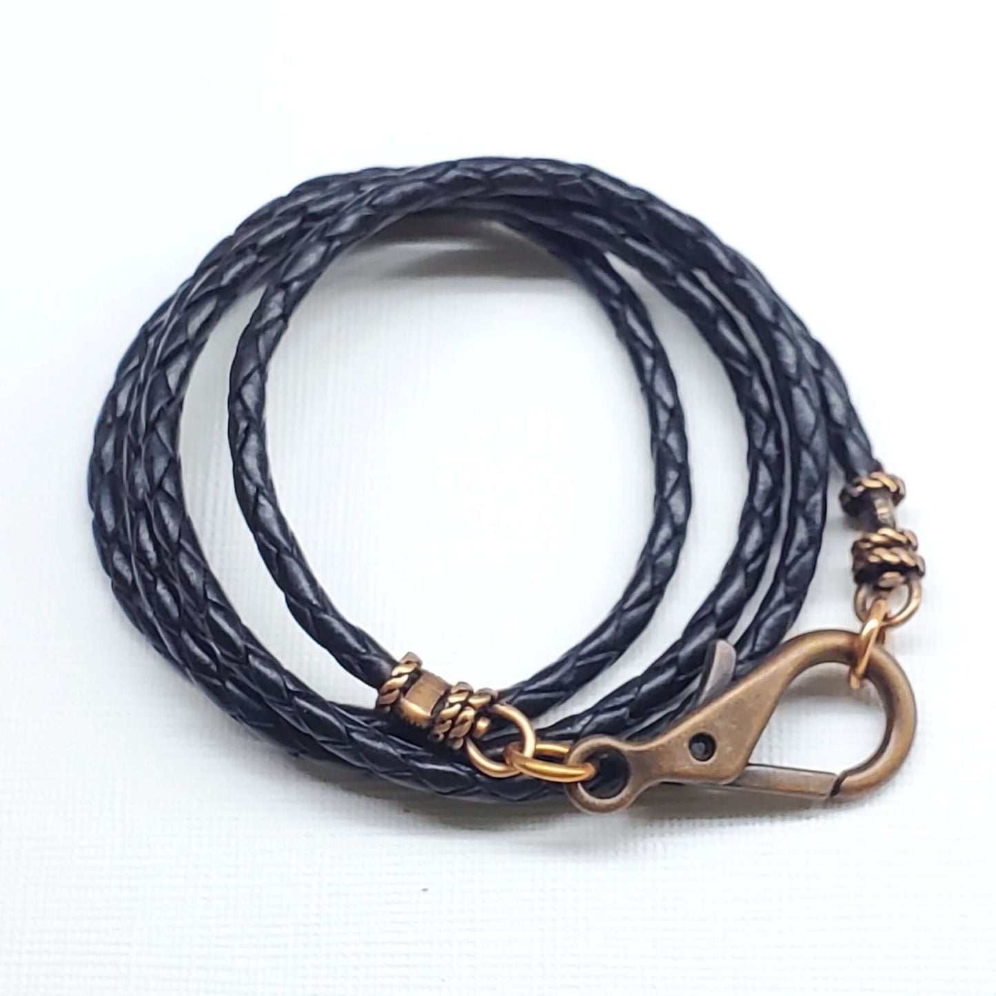 Black braided leather necklace with a brass clasp on a white background