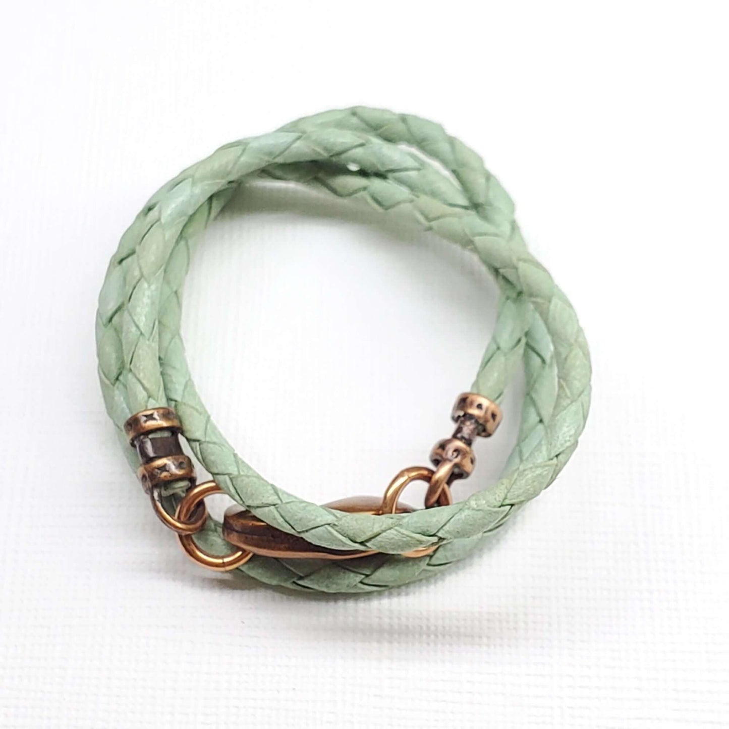 Green braided  necklace with bronze accents on a white background