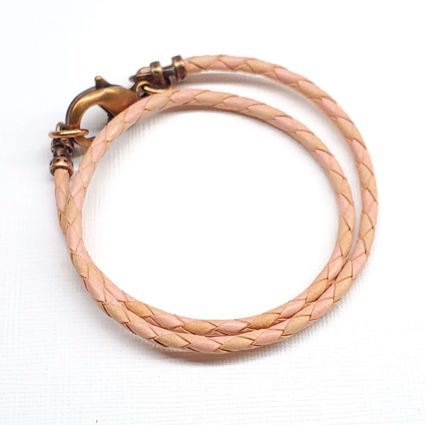 Braided beige leather  necklace with a bronze clasp on a white background