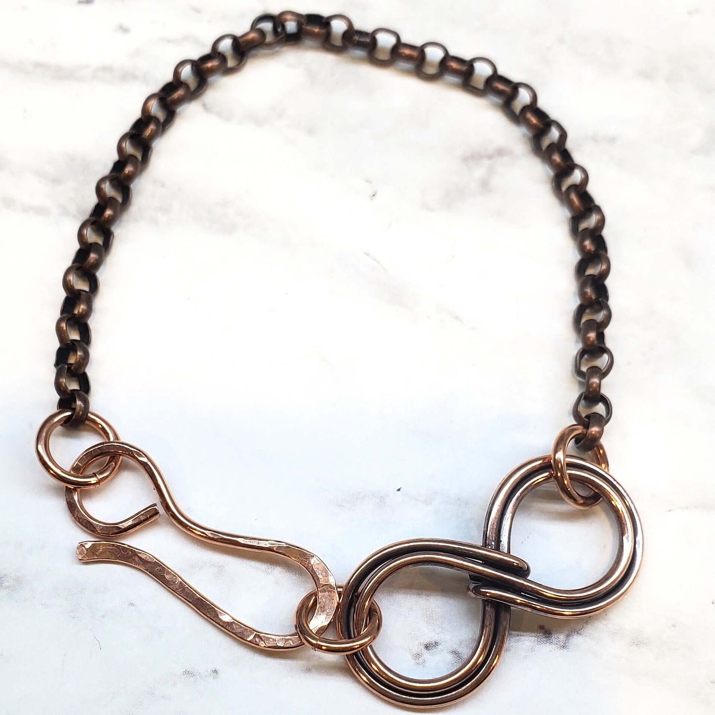 Copper infinity bracelet on a marble surface
