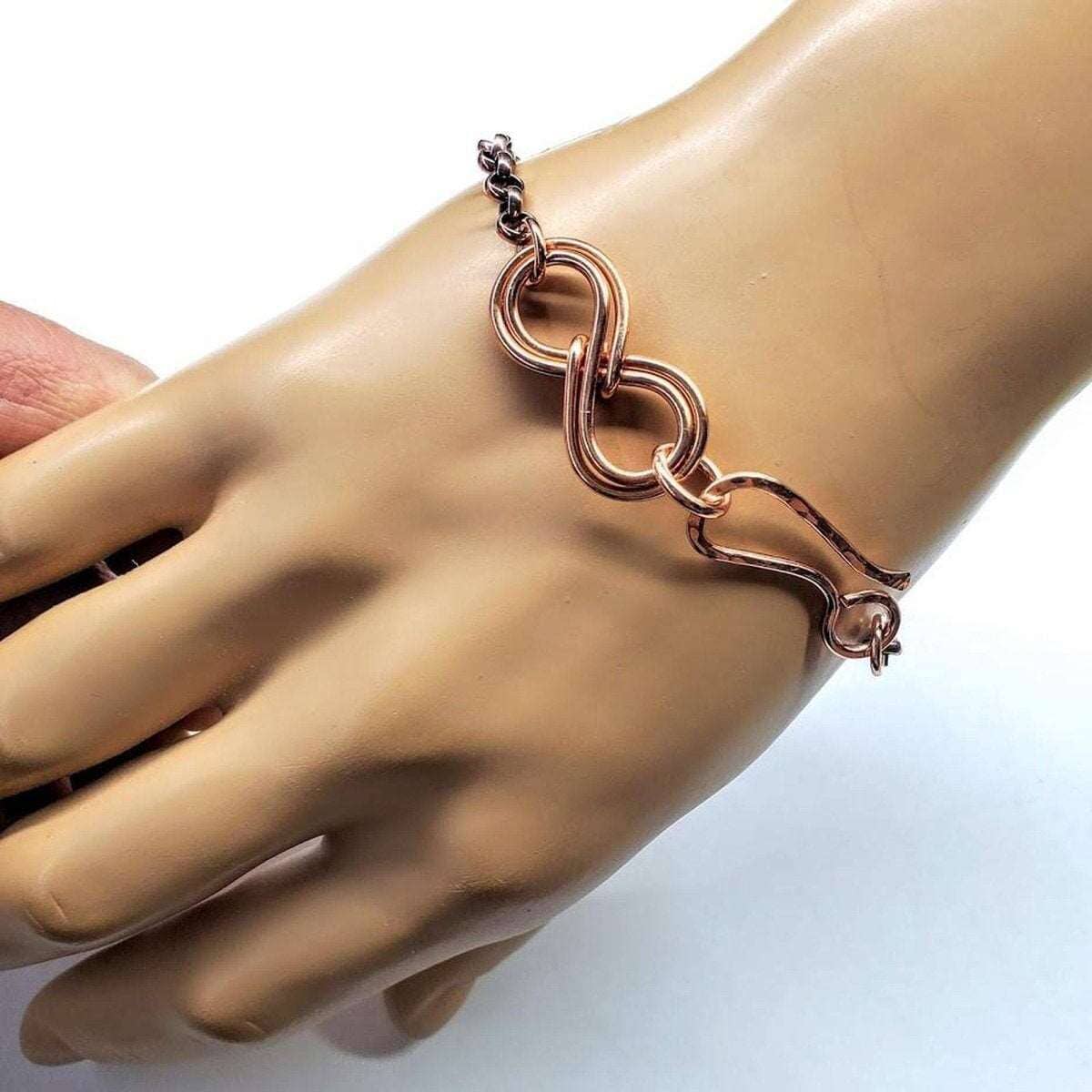Rose gold bracelet on a mannequin hand against a white background