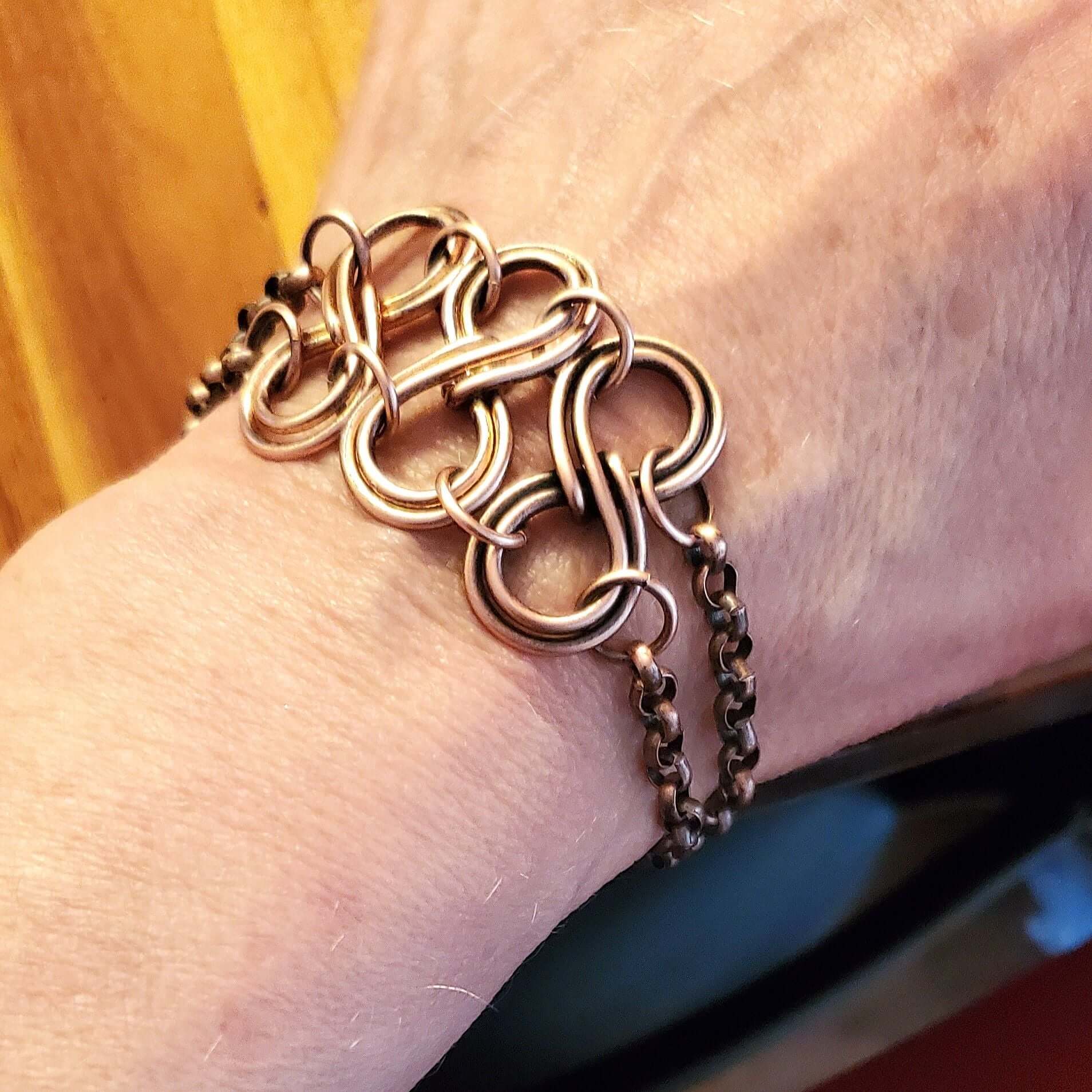 Close-up of a person wearing a rose gold chain bracelet on a blurred background