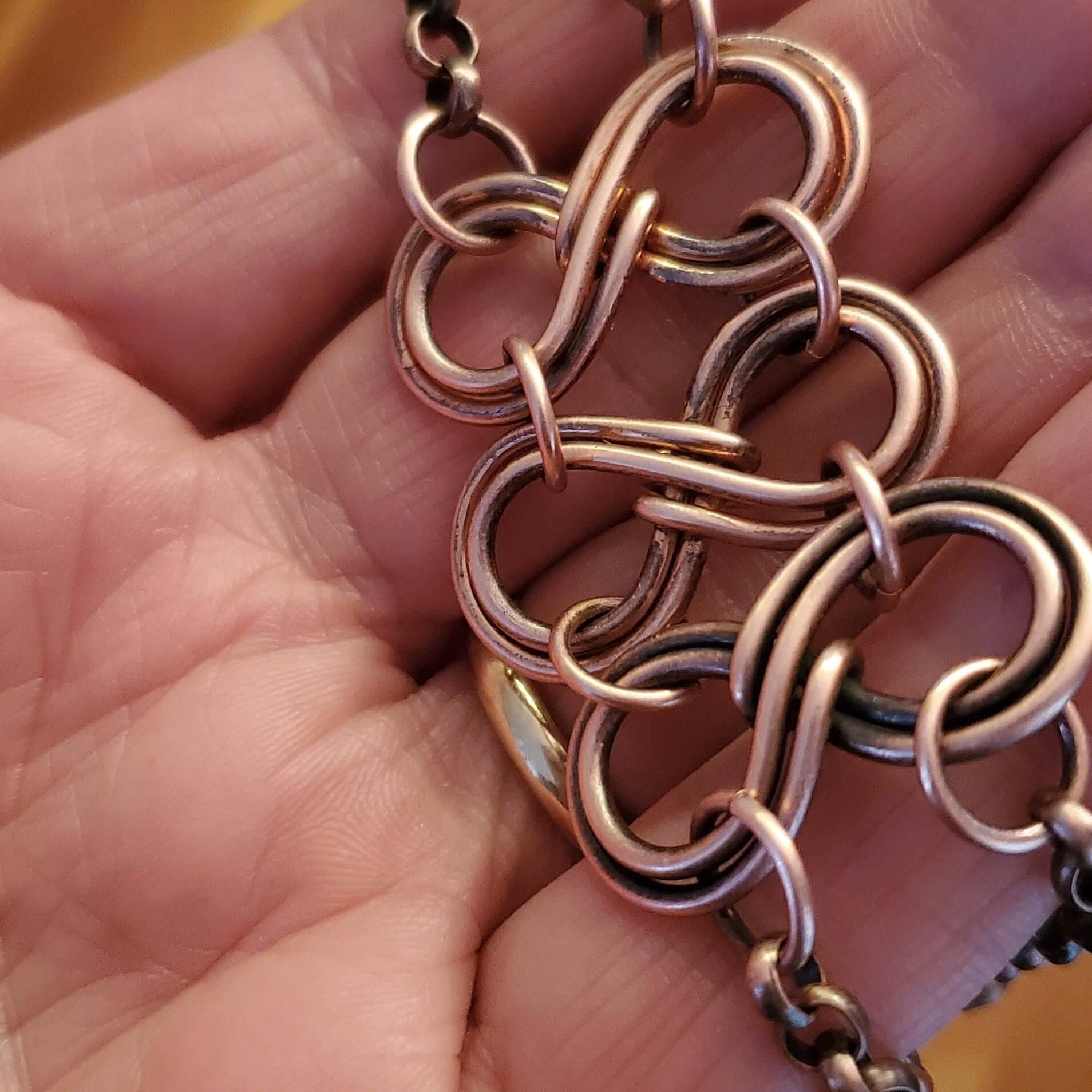 Close-up of a hand holding a copper chain necklace.