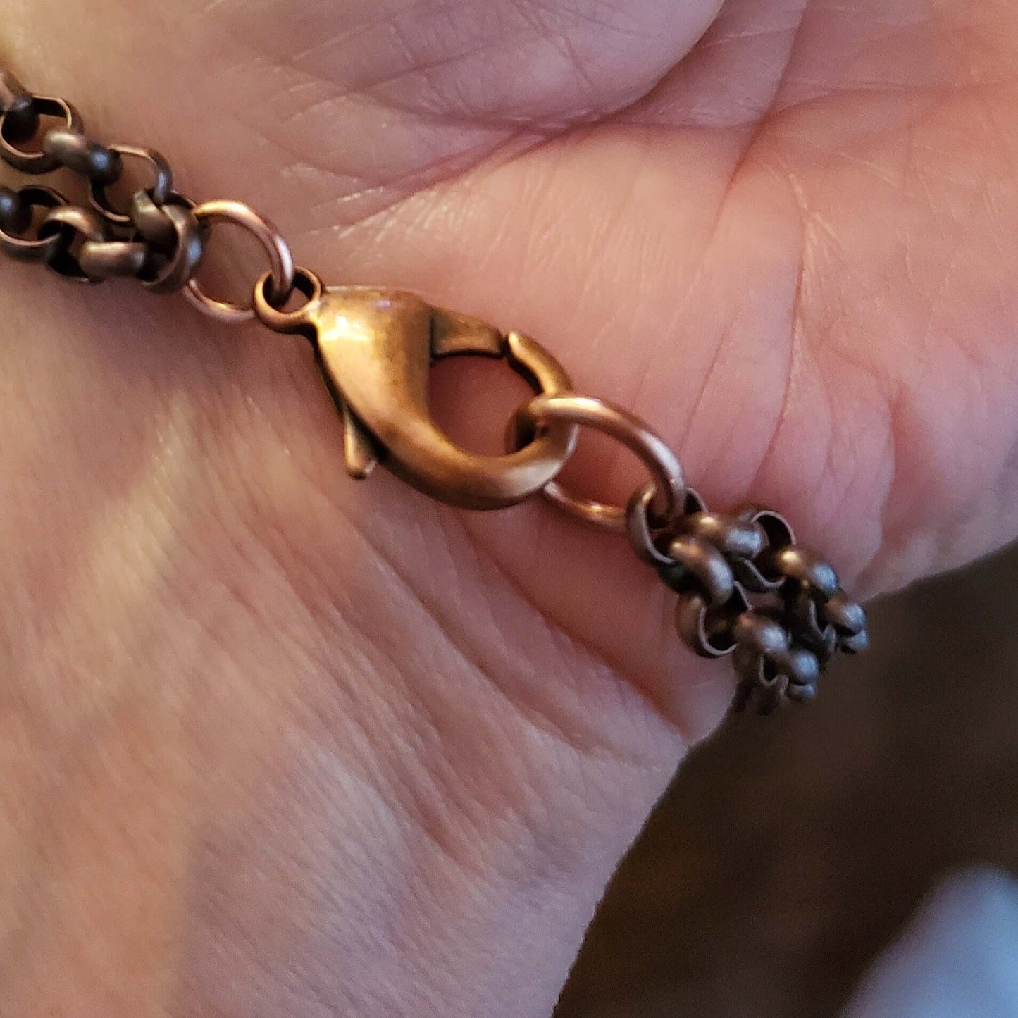Close-up of a bronze chain bracelet on a person's wrist.