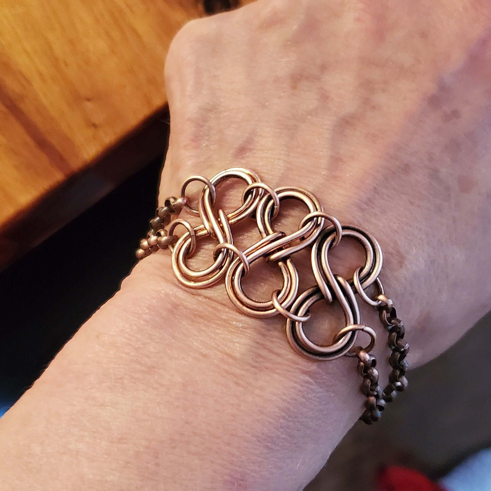 Copper chain bracelet on a wrist with a blurred background