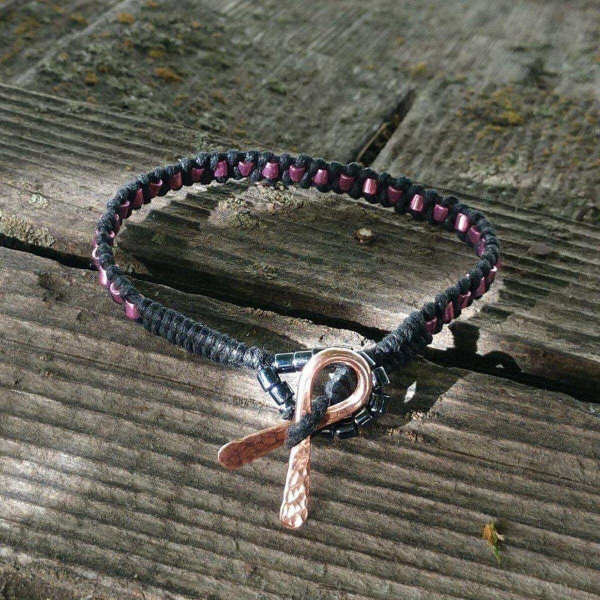 Bracelet with pink ribbon charm on a wooden surface